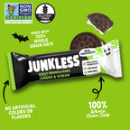 A Junkless Chewy Granola Bar in Cookies & Cream flavor, shown wrapped in a black and white wrapper with a cartoon ghost. The background is bright green with promotional text, a Non-GMO Project Verified badge, a Gluten Free badge, and an illustration of the cookie bar.