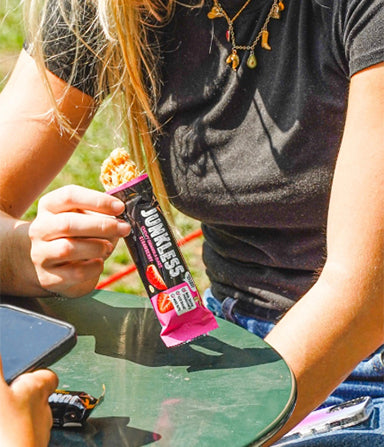 Person holding a Junkless strawberry chewy granola bar outside