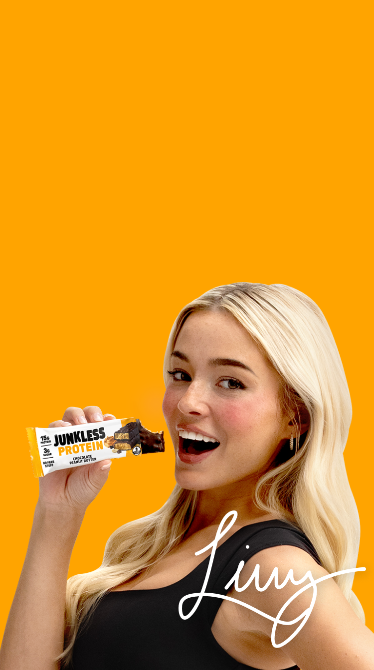 Woman holding a Junkless protein bar against an orange background
