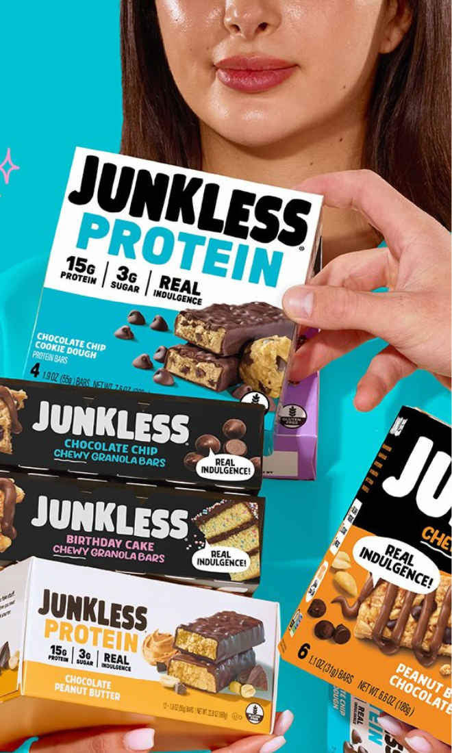 girl holding junkless protein bar boxes and granola bar boxes with a hand reaching in to take one off the top