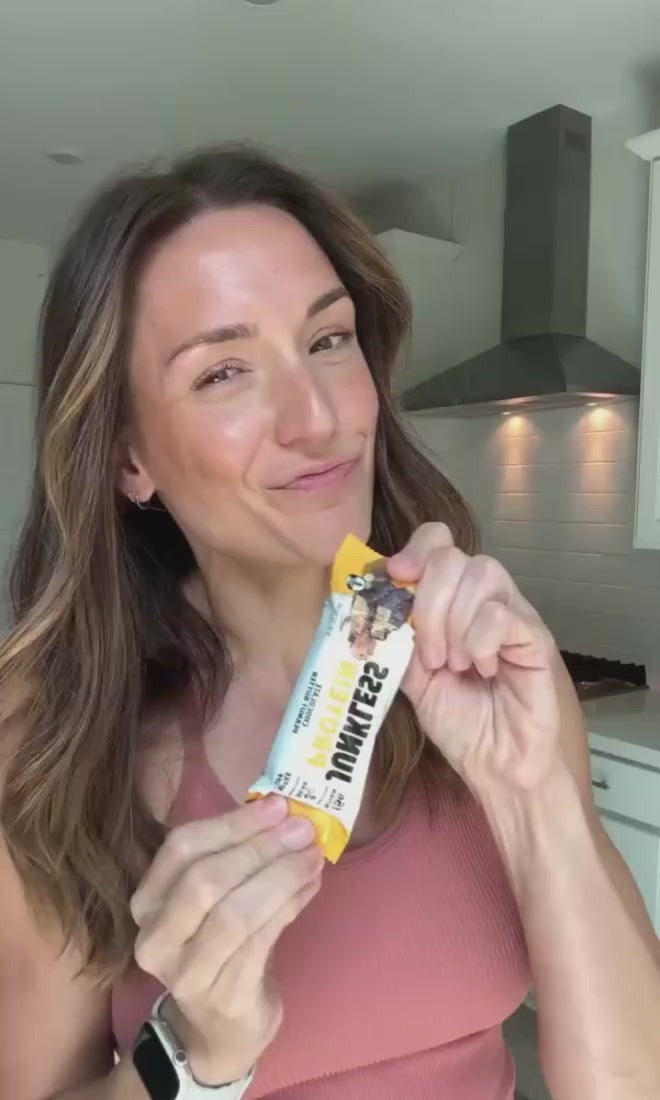 Women holding a Junkless protein bar in her kitchen